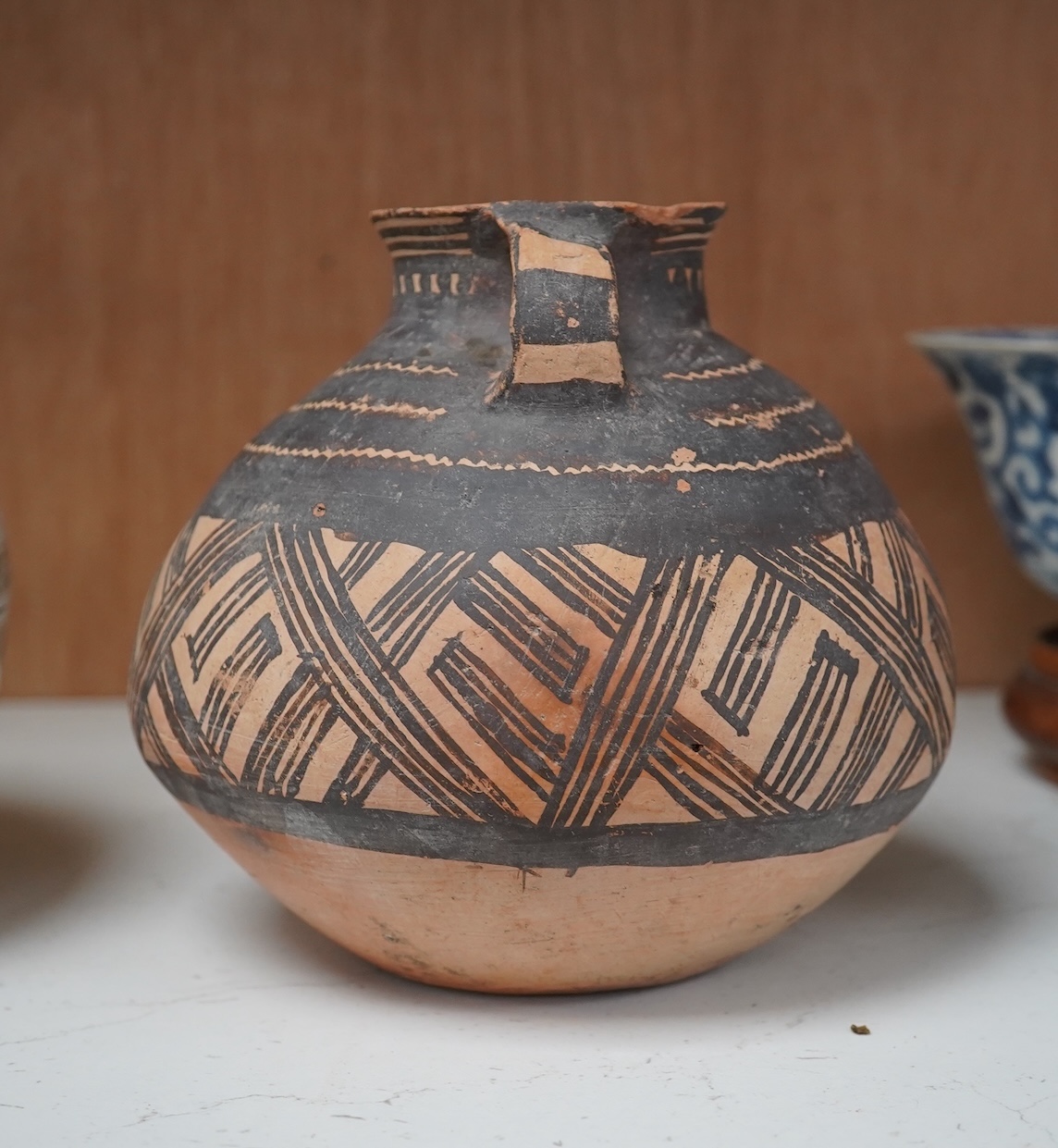 A Chinese neolithic pottery two handled jar - 14cm tall. Condition - fair to good, Provenance: the vendor‘s parents lived in Hong Kong from 1947 and bought the jar from a specialist dealer before 1980.